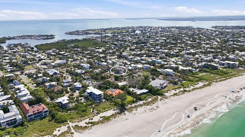 An aerial view shows a coastal neighborhood with a circled house near the beach — 115 AQUA LANE, HOLMES BEACH, FL