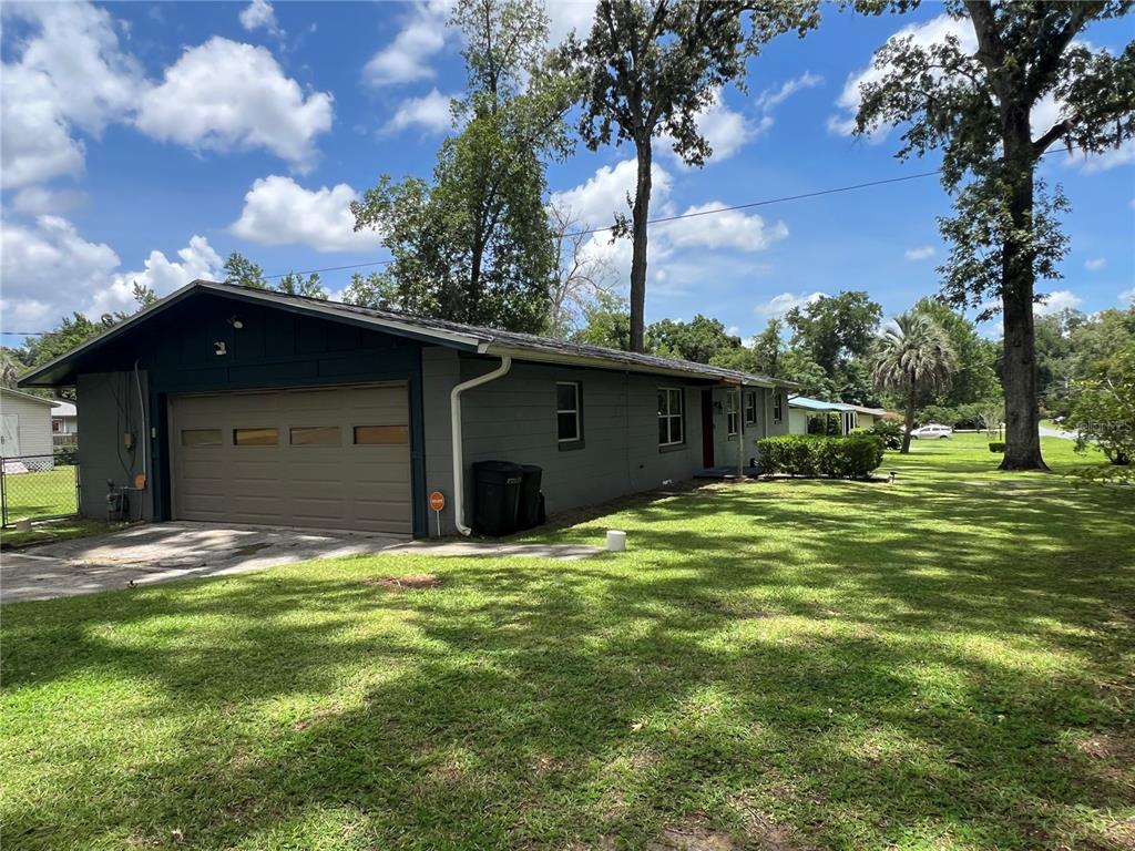 A gray single-story house features a tan garage door and a large grassy yard — 2720 SE 8TH AVENUE, OCALA, FL