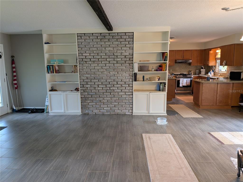 A living room features a gray brick fireplace flanked by white built-in shelving and tile flooring — 2720 SE 8TH AVENUE, OCALA, FL