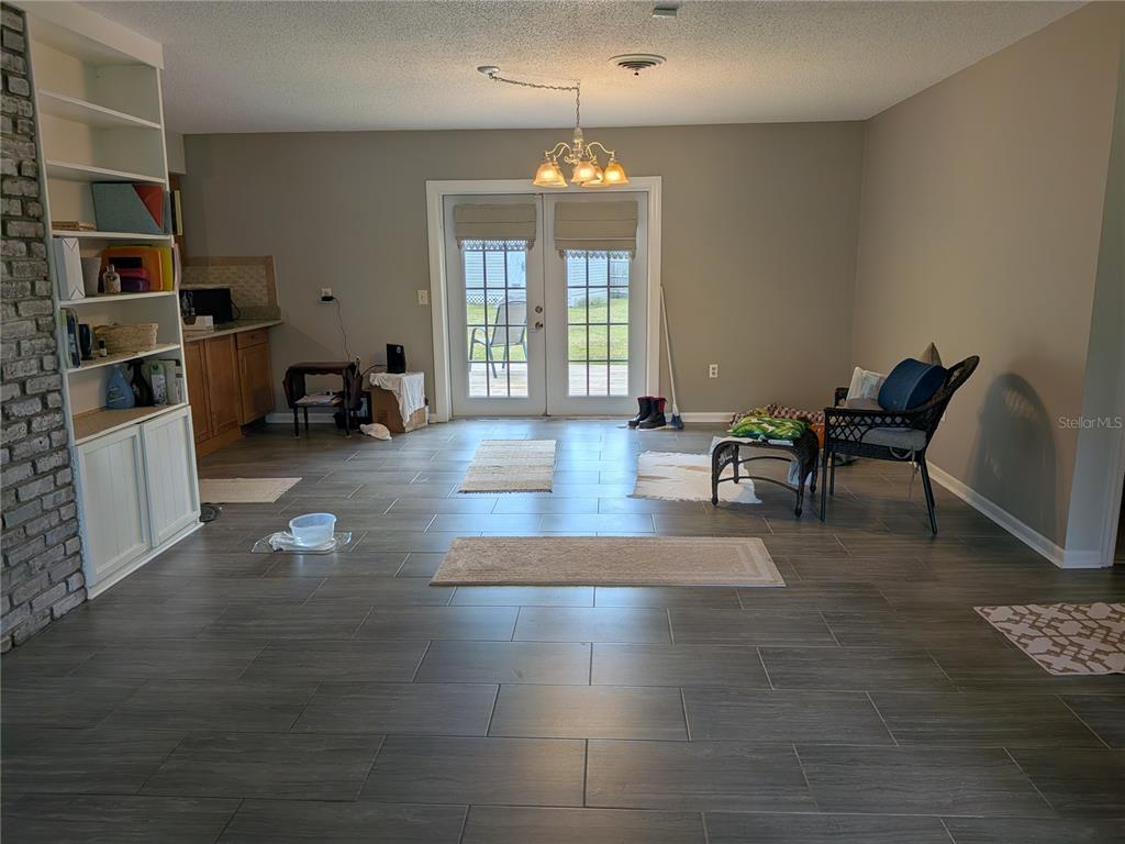 A room with gray tile flooring, a brick fireplace, built-in shelving, and French doors — 2720 SE 8TH AVENUE, OCALA, FL