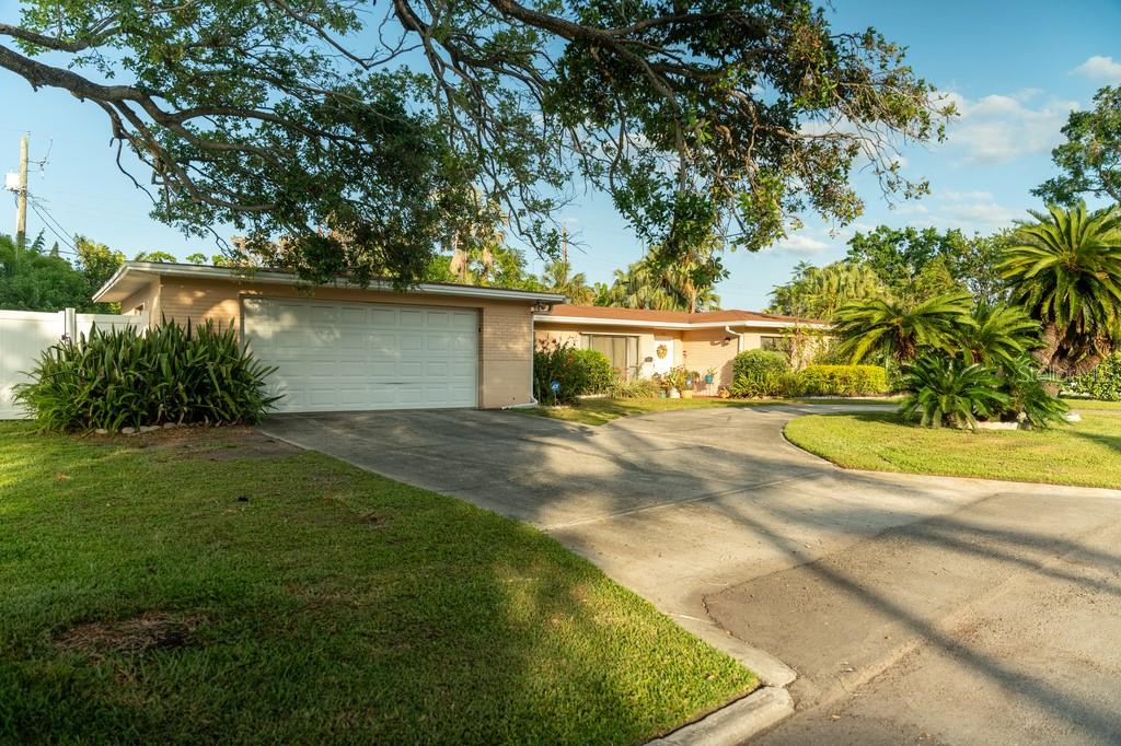 A single-story house with a white garage door, a concrete driveway, and mature landscaping — 631 LUZON AVENUE, TAMPA, FL