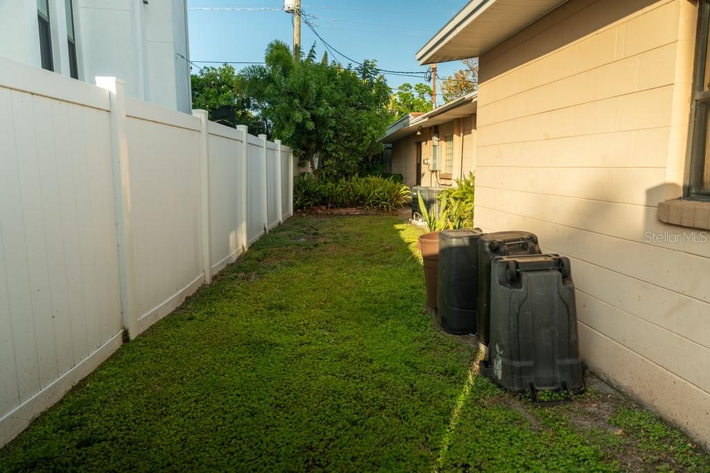 A narrow grassy side yard between a white vinyl fence and a beige house exterior — 631 LUZON AVENUE, TAMPA, FL