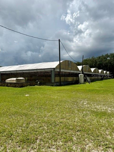A long greenhouse structure with a white roof sits on a grassy lot — 33322 COUNTY ROAD 437, SORRENTO, FL