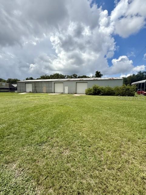 A long, metal-sided industrial warehouse building sits on a large, grassy lot under a cloudy sky — 33322 COUNTY ROAD 437, SORRENTO, FL
