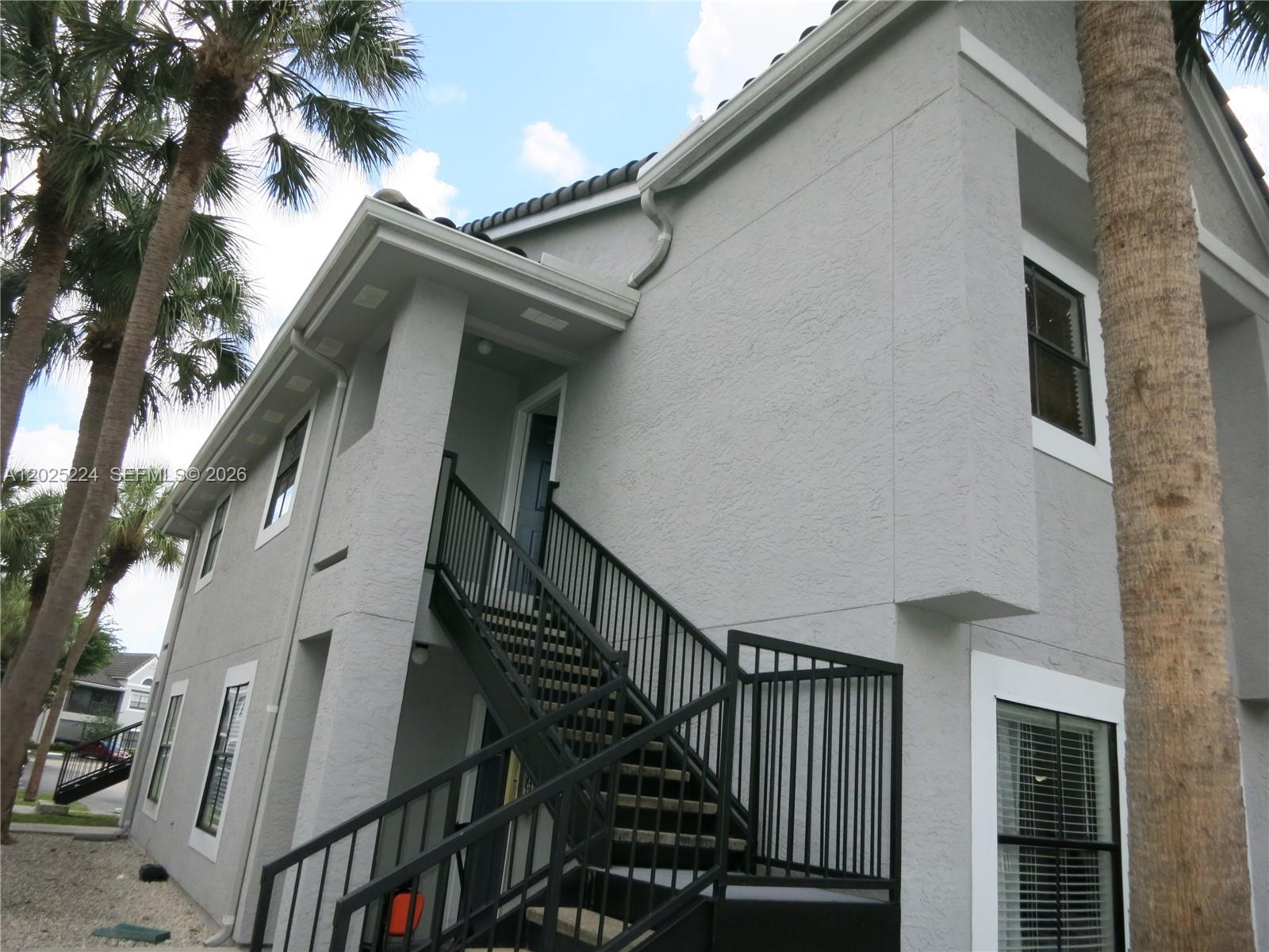 A two-story gray stucco building features an exterior metal staircase leading to an upper entrance — 15060 SW 103rd Ter # 6203, Miami FL 33196, MIAMI, FL