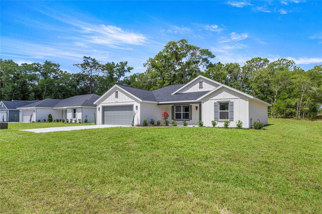A white single-story house with a gray garage and dark roof sits on a lawn — 4020 SW 156TH COURT, OCALA, FL