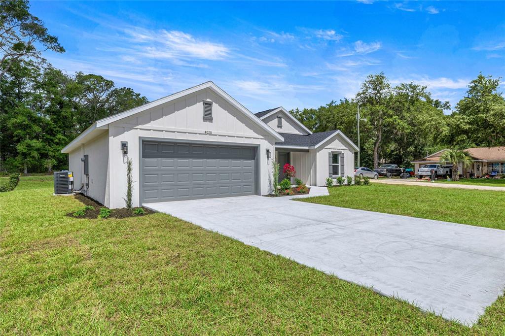 A single-story house with a gray garage door, white siding, and a concrete driveway — 4020 SW 156TH COURT, OCALA, FL