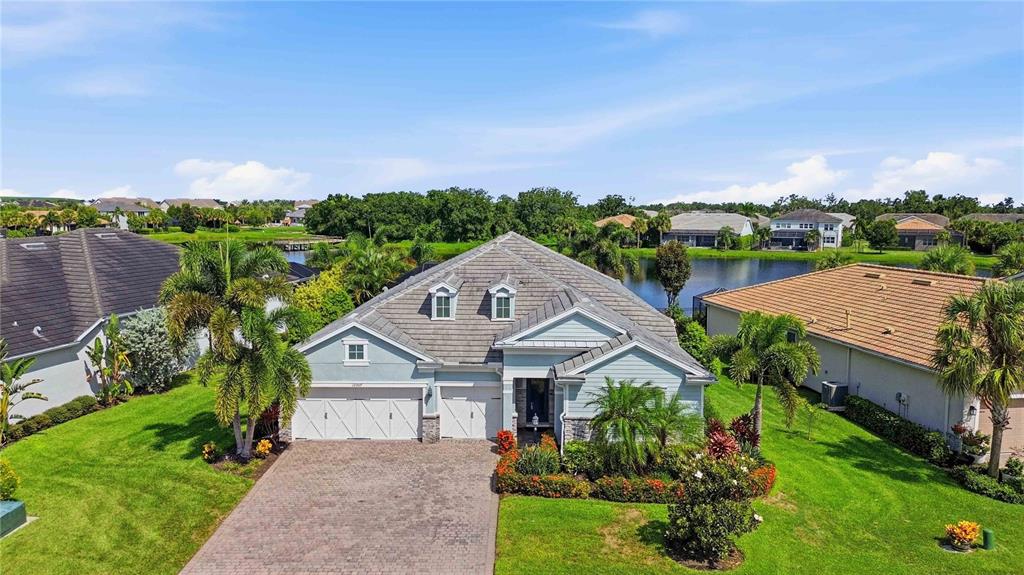 An aerial view of a light blue single-story house with a paver driveway and lake — 12307 SEABROOK AVENUE, BRADENTON, FL