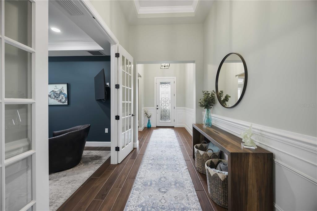 A hallway with dark wood floors, a runner rug, a console table, and French doors — 12307 SEABROOK AVENUE, BRADENTON, FL