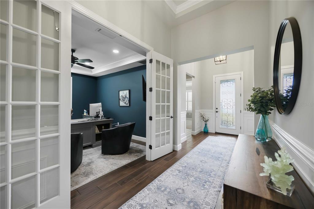 A hallway with a runner rug leads to a front door and a home office — 12307 SEABROOK AVENUE, BRADENTON, FL