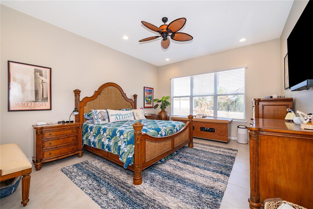 A bedroom features a tropical-style wooden bed, a blue patterned rug, and a ceiling fan — 7789 FOUR SEASONS BOULEVARD, KISSIMMEE, FL