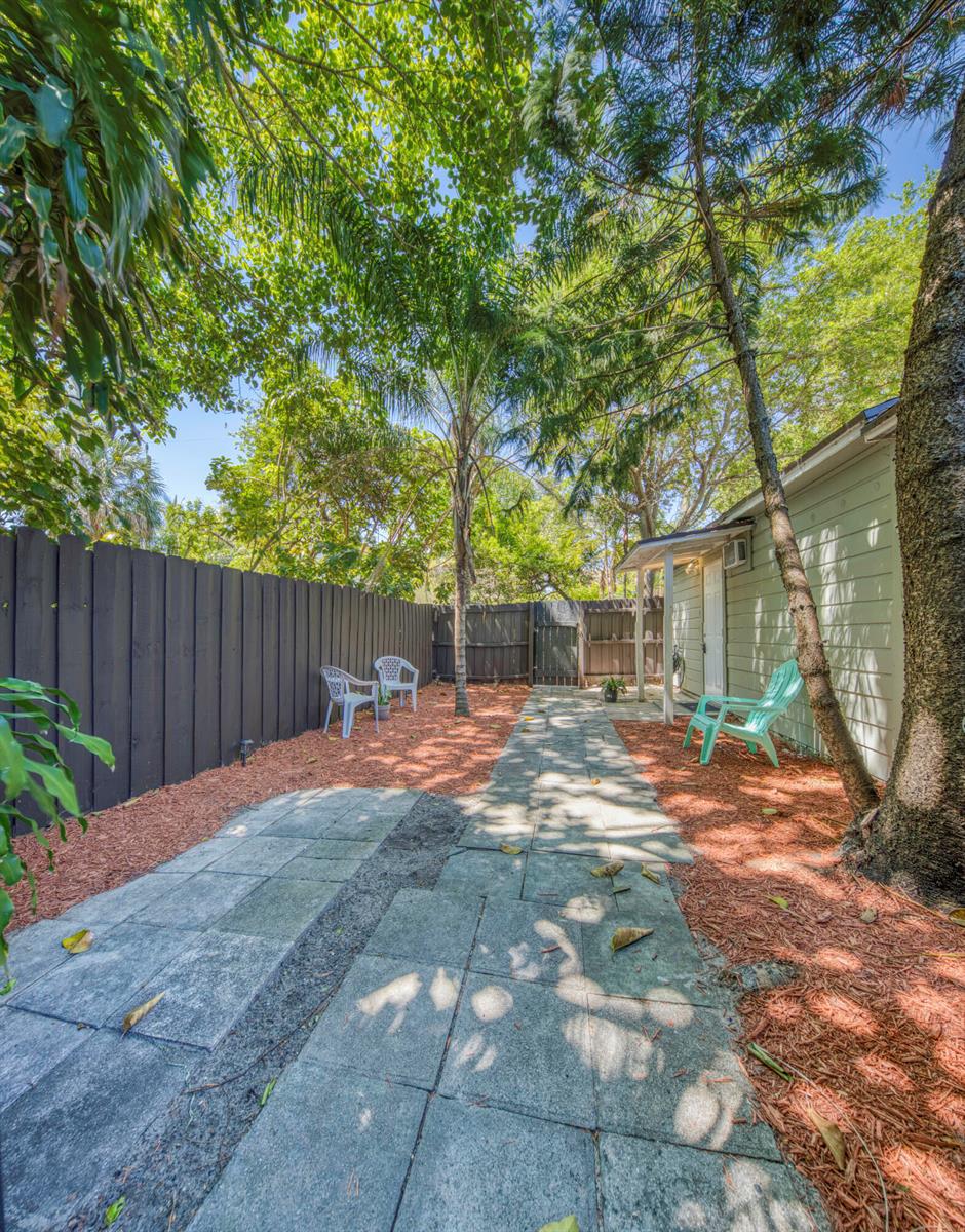 A backyard features a stone walkway, mulch ground cover, a wooden fence, and outdoor seating — 519 S M Street, FL 33460, FL