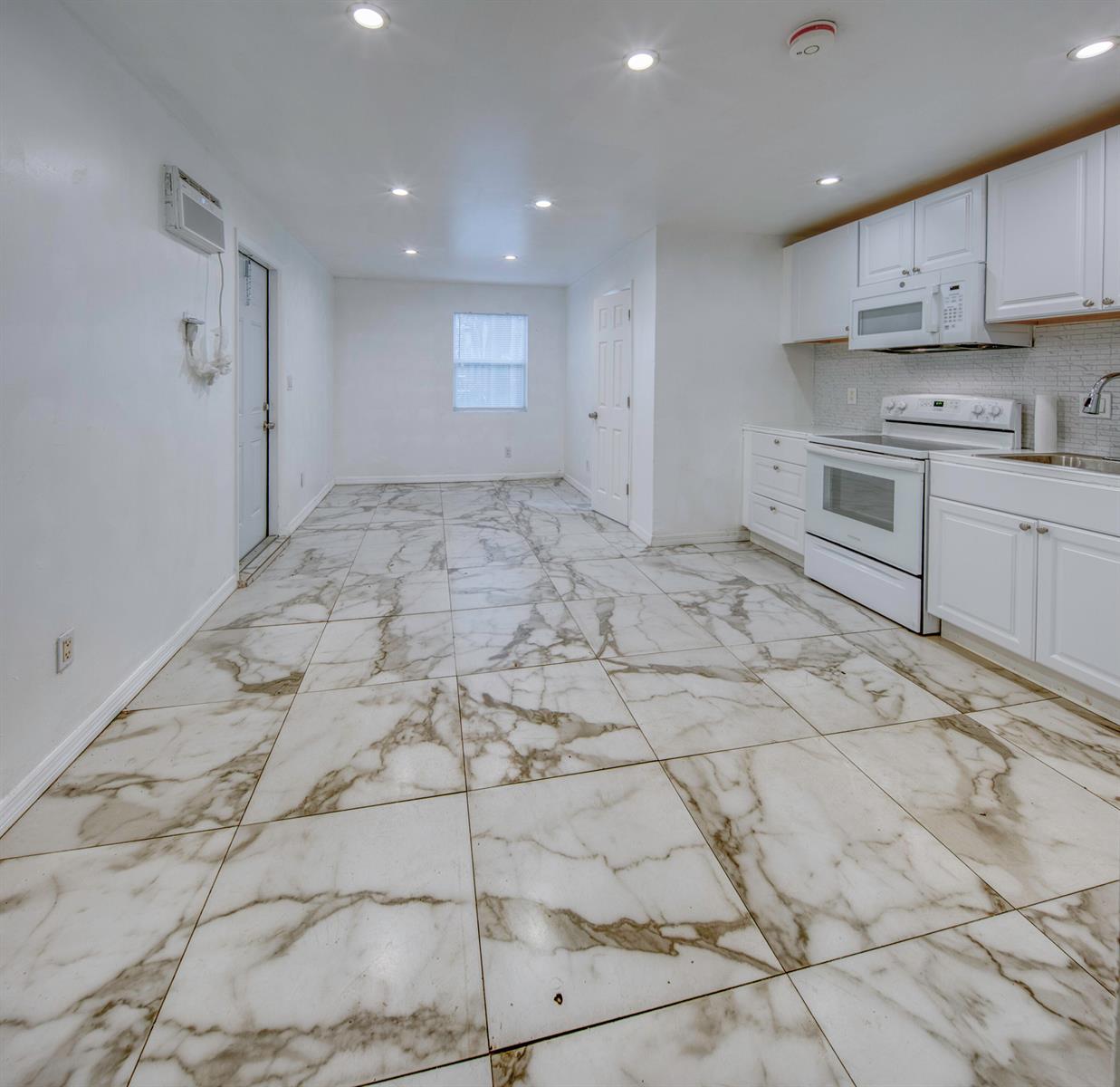 A kitchen with white cabinets, white appliances, and large marble-patterned floor tiles — 519 S M Street, FL 33460, FL