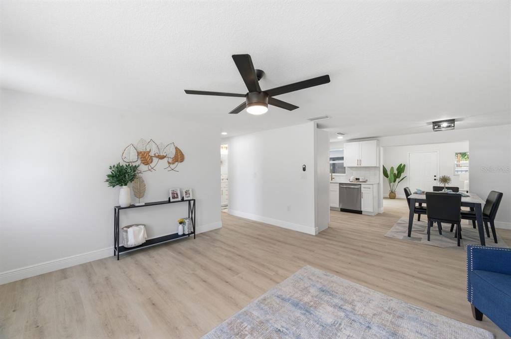 A living room with light wood flooring, a ceiling fan, and an open dining area — 4760 SEVILLE DRIVE, SARASOTA, FL