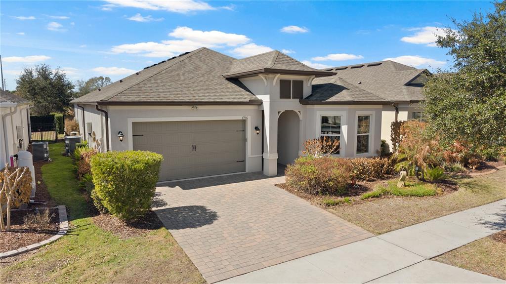 A single-story house with a beige stucco exterior, a two-car garage, and a paved driveway — 7956 HANSON BAY PLACE, KISSIMMEE, FL
