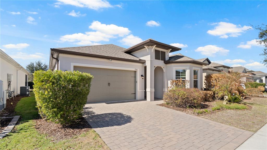 A single-story house with a beige garage, paved driveway, and a small front yard — 7956 HANSON BAY PLACE, KISSIMMEE, FL