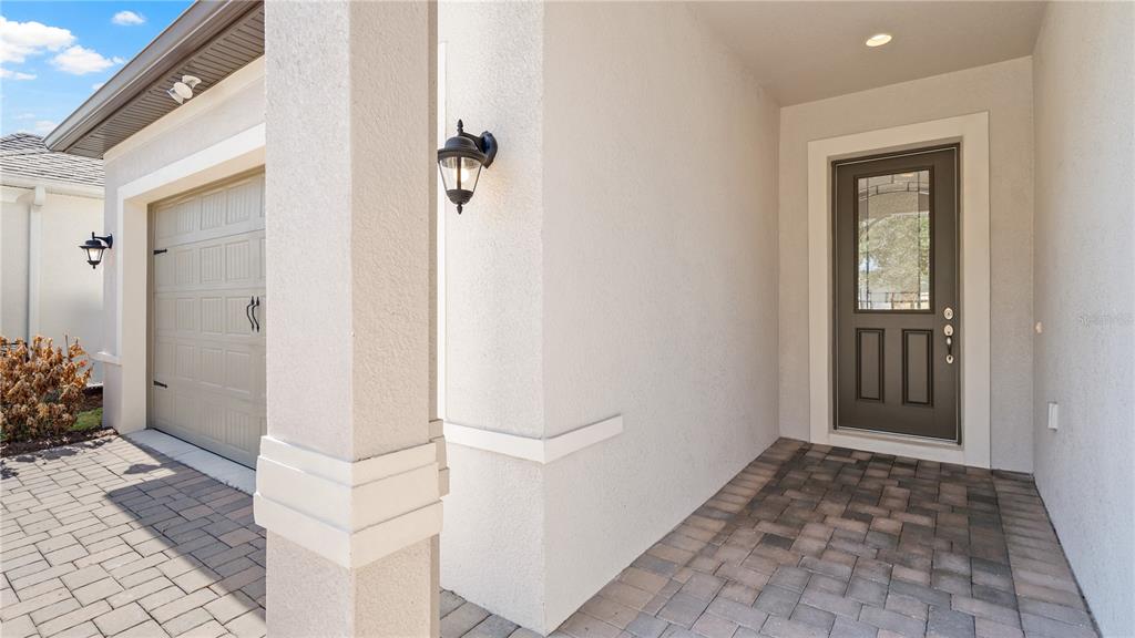 A paved entryway features a dark gray front door and a beige garage door — 7956 HANSON BAY PLACE, KISSIMMEE, FL