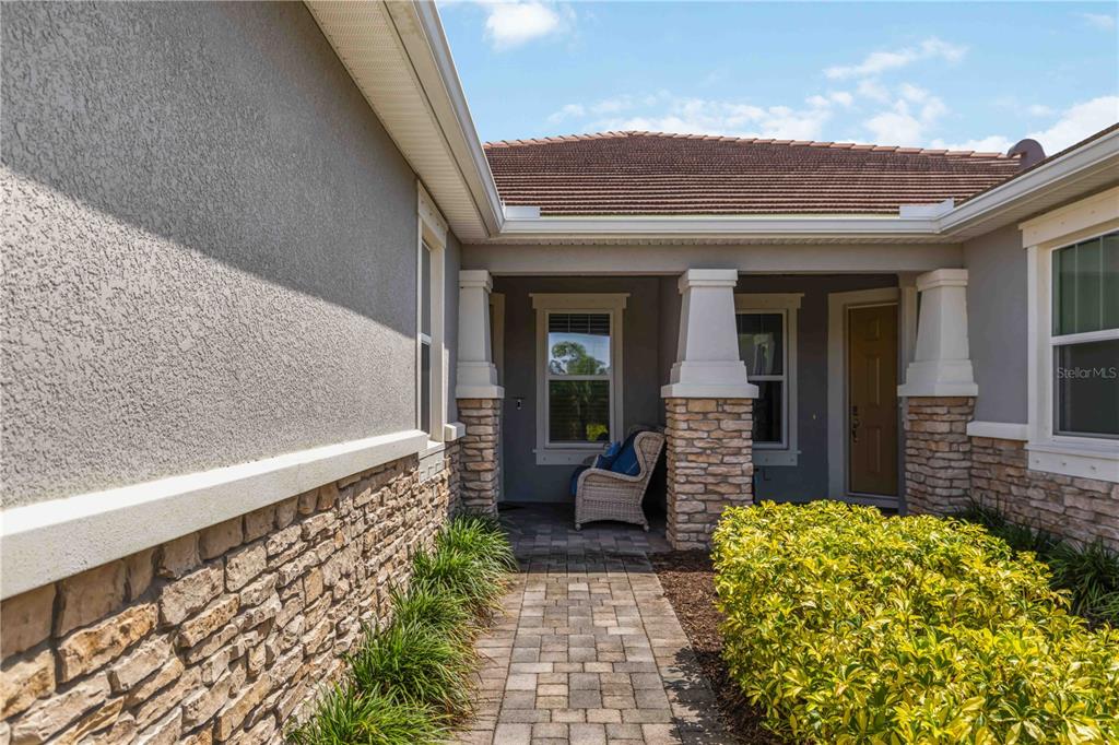 A stone-accented entryway features a paved walkway leading to a covered porch with columns — 8788 RAIN SONG ROAD UNIT 384, SARASOTA, FL