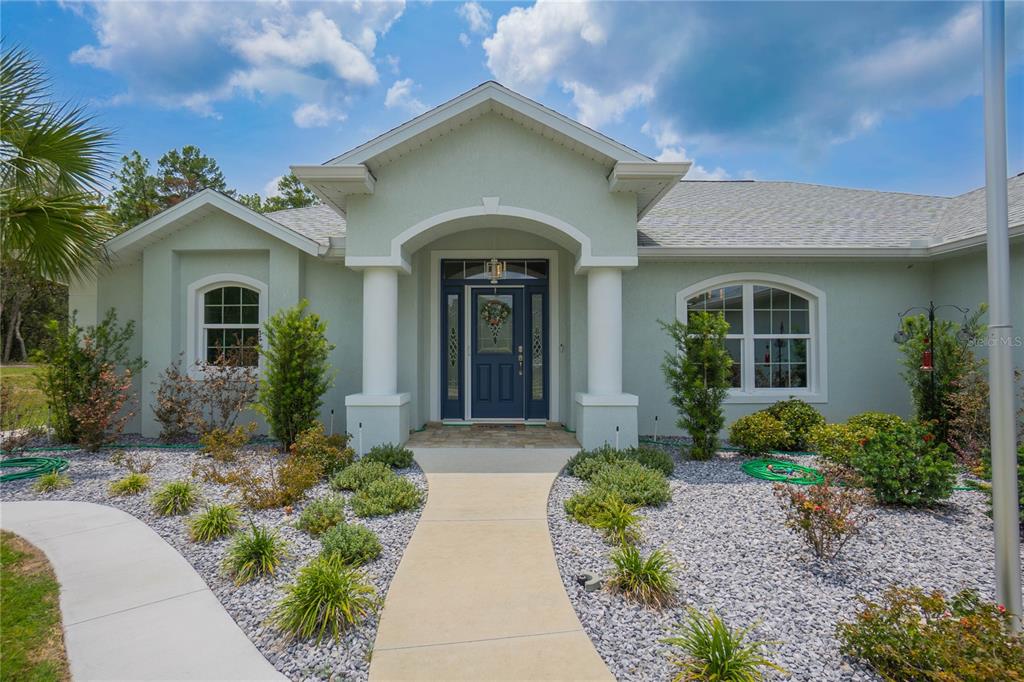 A light green house with a covered entryway, white columns, and a landscaped front yard — 4136 W FINDLAY STREET, CITRUS SPRINGS, FL