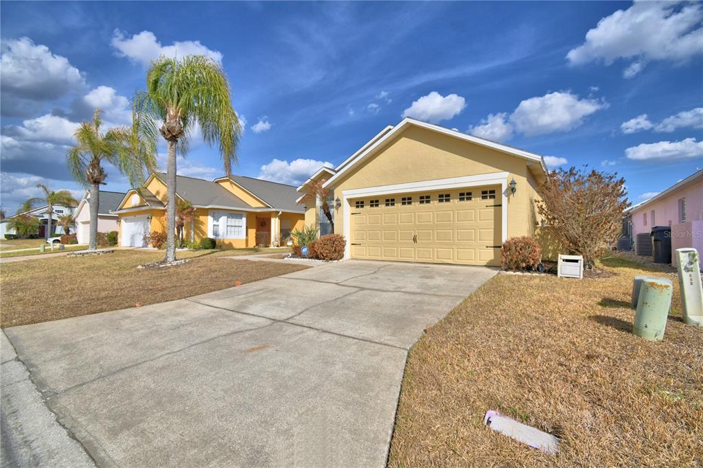 A yellow single-story house with a two-car garage and a concrete driveway — 459 TIVOLI CIRCLE, DAVENPORT, FL