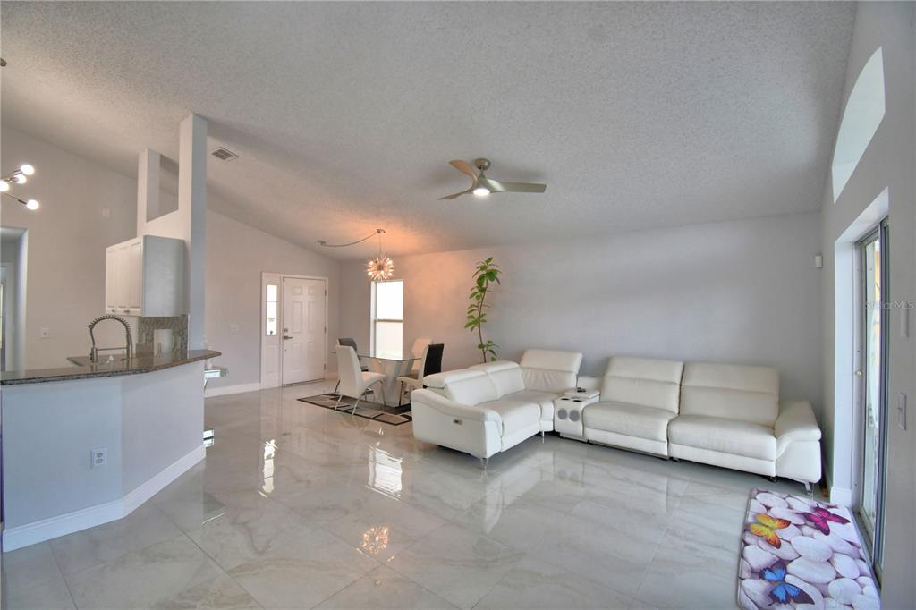 A bright open-concept living and dining area features white tile floors and a white sofa — 459 TIVOLI CIRCLE, DAVENPORT, FL
