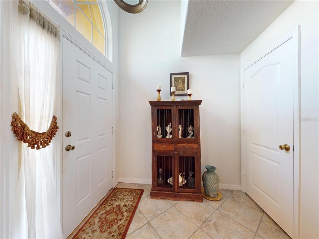 An entryway features a tiled floor, a wooden cabinet, and a white front door — 221 BELGIAN WAY, SANFORD, FL