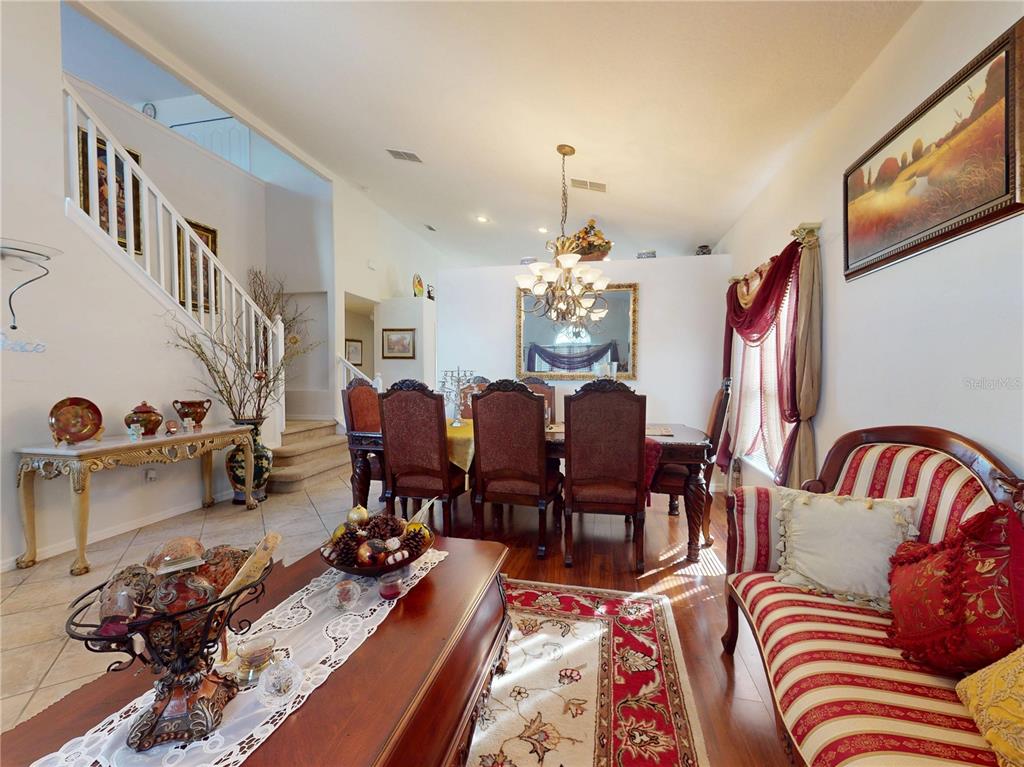 A dining room and living area feature a staircase, chandelier, and traditional furniture — 221 BELGIAN WAY, SANFORD, FL