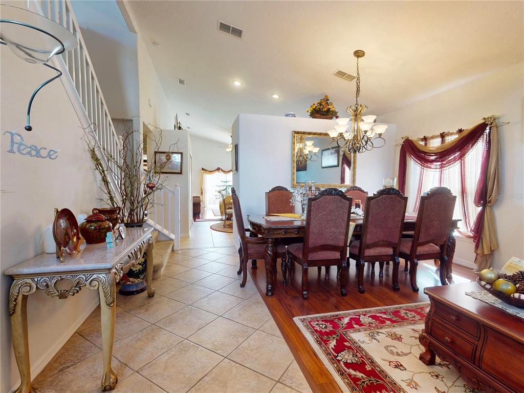 A dining room with a wooden table and chairs sits next to a tiled entryway — 221 BELGIAN WAY, SANFORD, FL