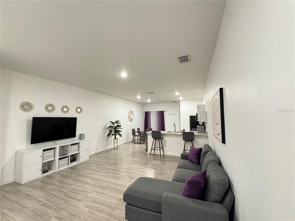 An open-concept living room features a grey sectional sofa, white media console, and kitchen island — 699 W KALEY STREET, ORLANDO, FL