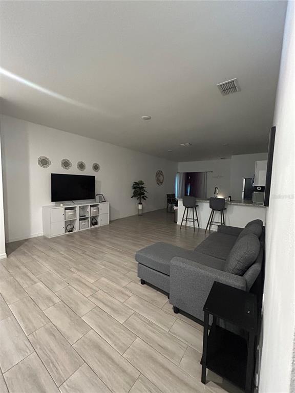 An open-concept living room features light tile flooring, a gray sectional sofa, and a kitchen — 699 W KALEY STREET, ORLANDO, FL