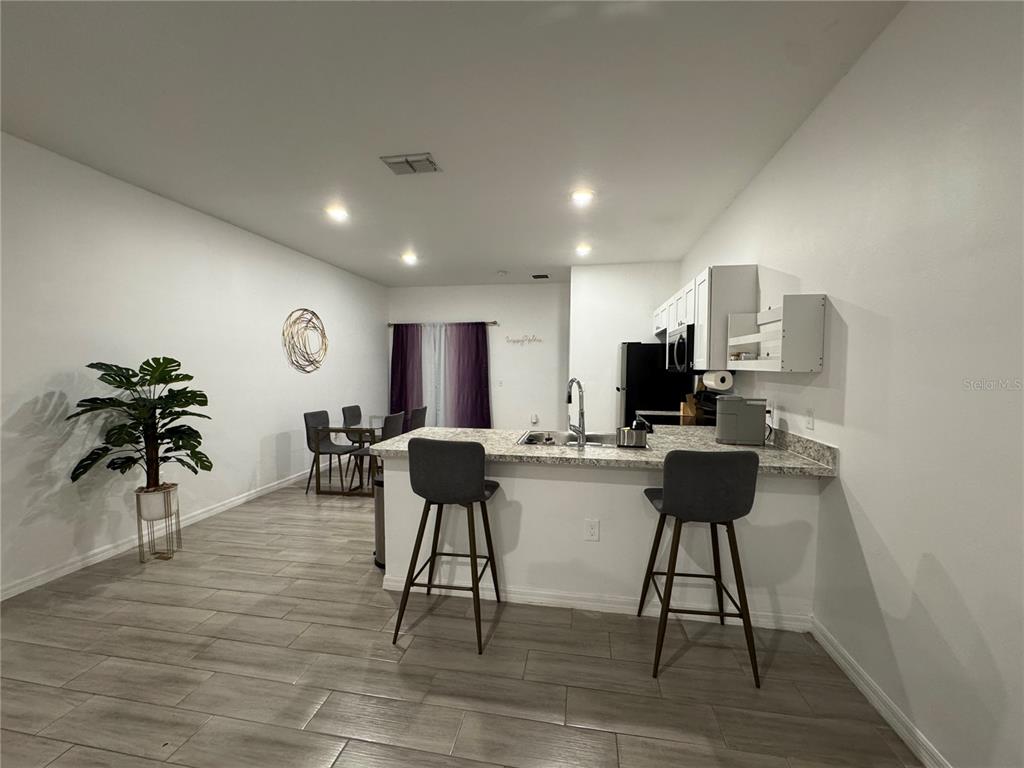 A kitchen with a breakfast bar, gray barstools, and light wood-look tile flooring — 699 W KALEY STREET, ORLANDO, FL