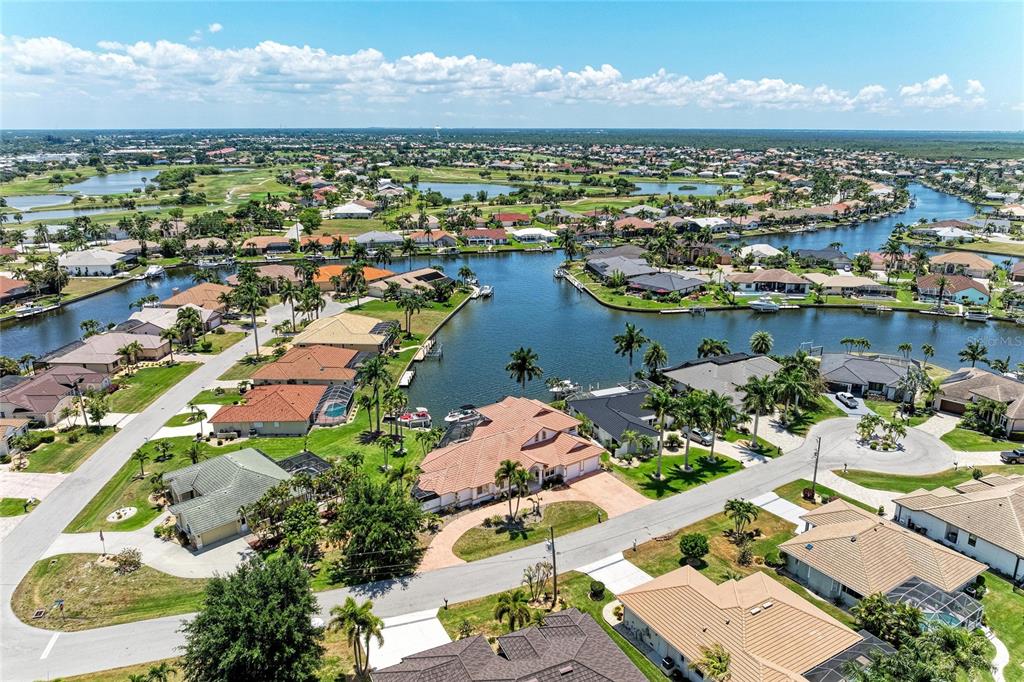 An aerial view shows a residential neighborhood with houses situated along a winding canal — 524 LA CARUNA COURT, PUNTA GORDA, FL