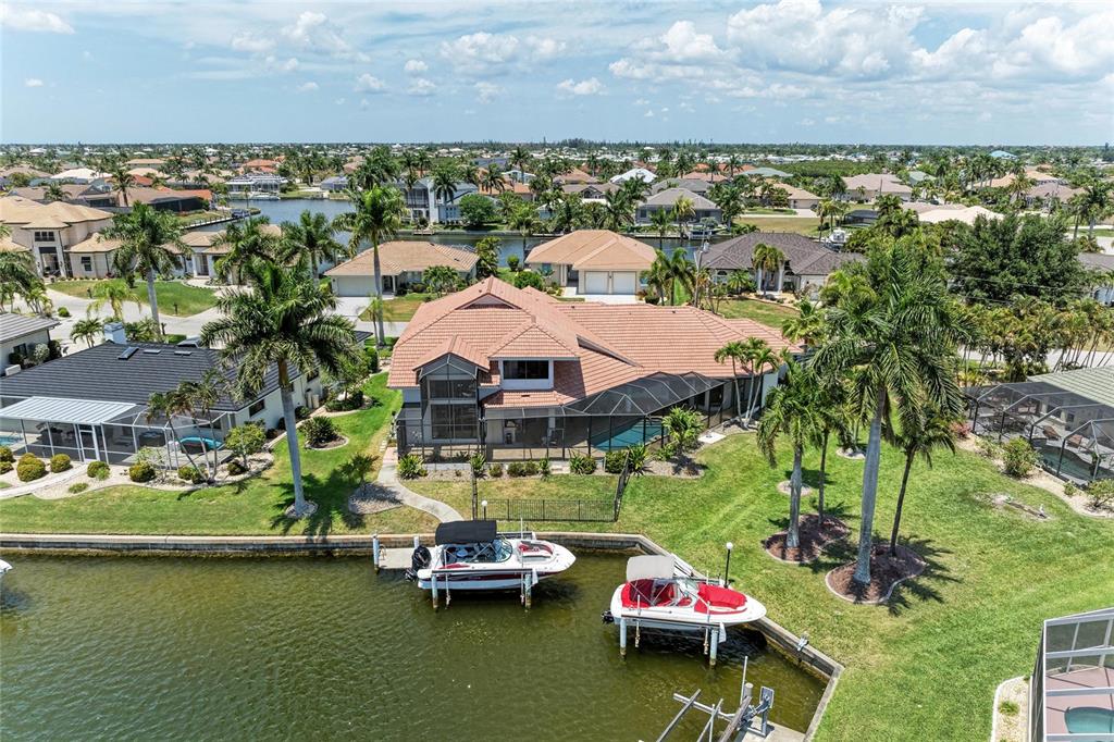An aerial view of a waterfront house with a pool, screened lanai, and two boat lifts — 524 LA CARUNA COURT, PUNTA GORDA, FL
