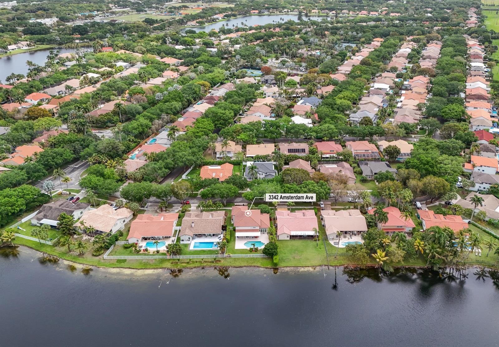 An aerial view shows a row of waterfront houses with swimming pools along a lake — 3342 Amsterdam Avenue, Cooper City FL 33026, COOPER CITY, FL