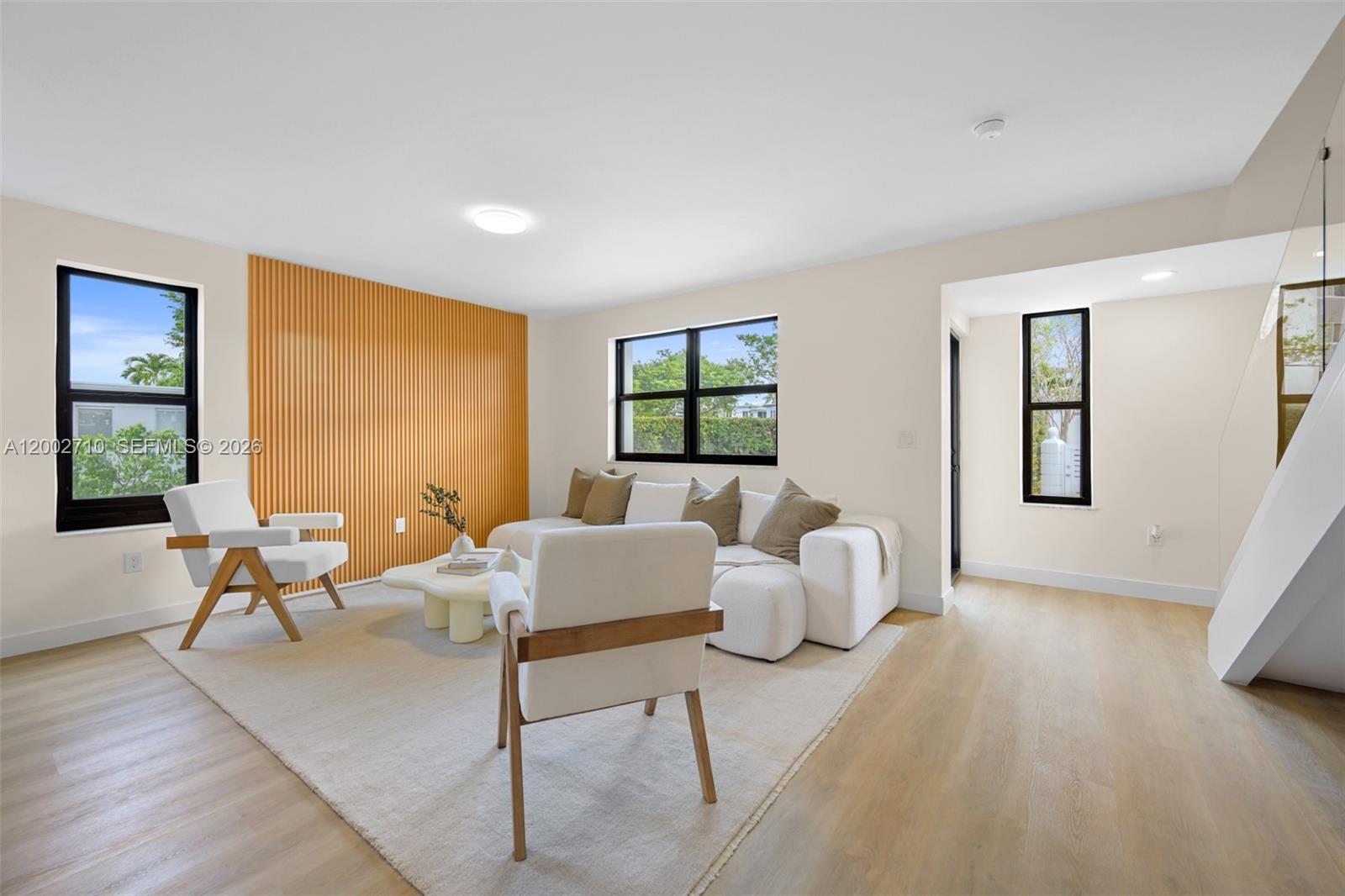 A living room features a slatted wood accent wall, white furniture, and light wood flooring — 7996 Crespi Blvd, Miami Beach FL 33141, MIAMI BEACH, FL