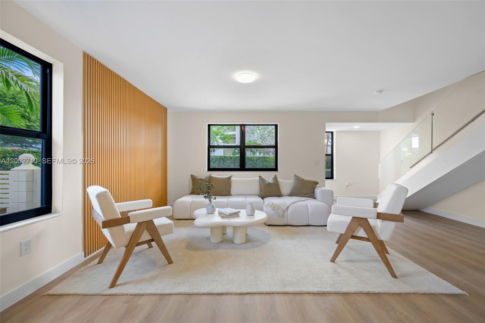 A living room features a slatted wood accent wall, white sofa, two chairs, and stairs — 7996 Crespi Blvd, Miami Beach FL 33141, MIAMI BEACH, FL