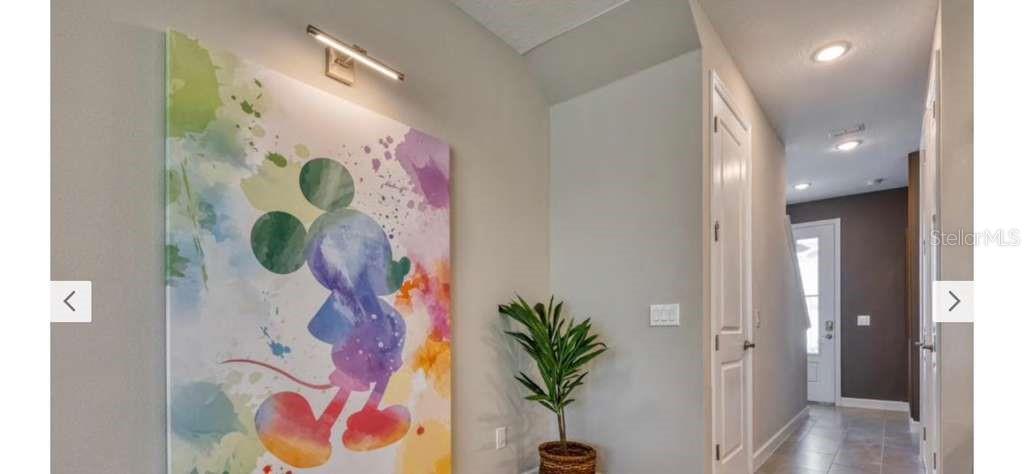 A hallway features a large Mickey Mouse watercolor painting, a potted plant, and recessed lighting — 8001 FORMOSA VALLEY, KISSIMMEE, FL