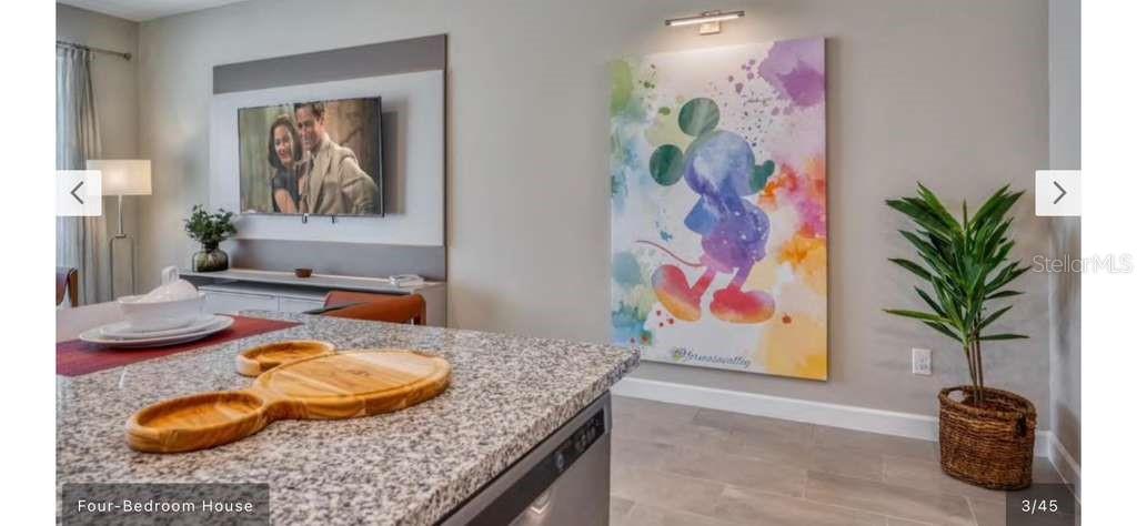 A kitchen island with a Mickey Mouse-shaped wooden tray sits before a living room wall — 8001 FORMOSA VALLEY, KISSIMMEE, FL