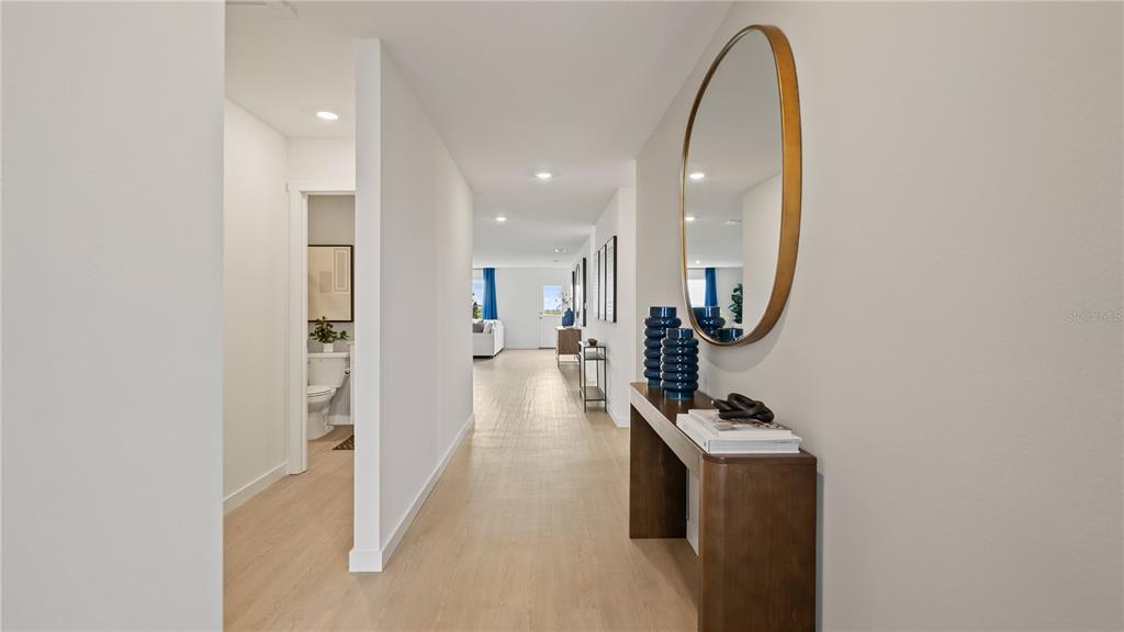 A hallway with light wood floors leads to a living area, featuring a console table — 527 ARTEMIS STREET, LAKE WALES, FL