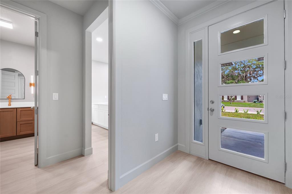 A bright entryway features light wood flooring, gray walls, and a modern door with glass panels — 2034 E GRANT AVENUE, ORLANDO, FL