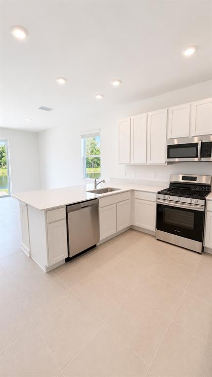 A modern kitchen features white cabinets, stainless steel appliances, and a quartz-topped island — 3045 CHROMATIC STREET, KISSIMMEE, FL