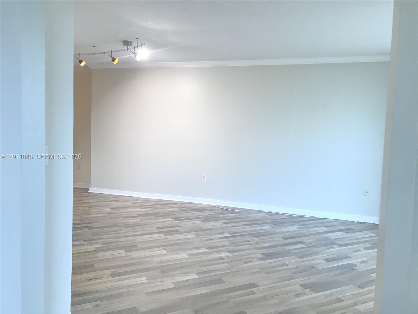 An empty room features light gray walls, wood-look laminate flooring, and a track lighting fixture — 9055 SW 73rd Ct # 1903, Miami FL 33156, MIAMI, FL