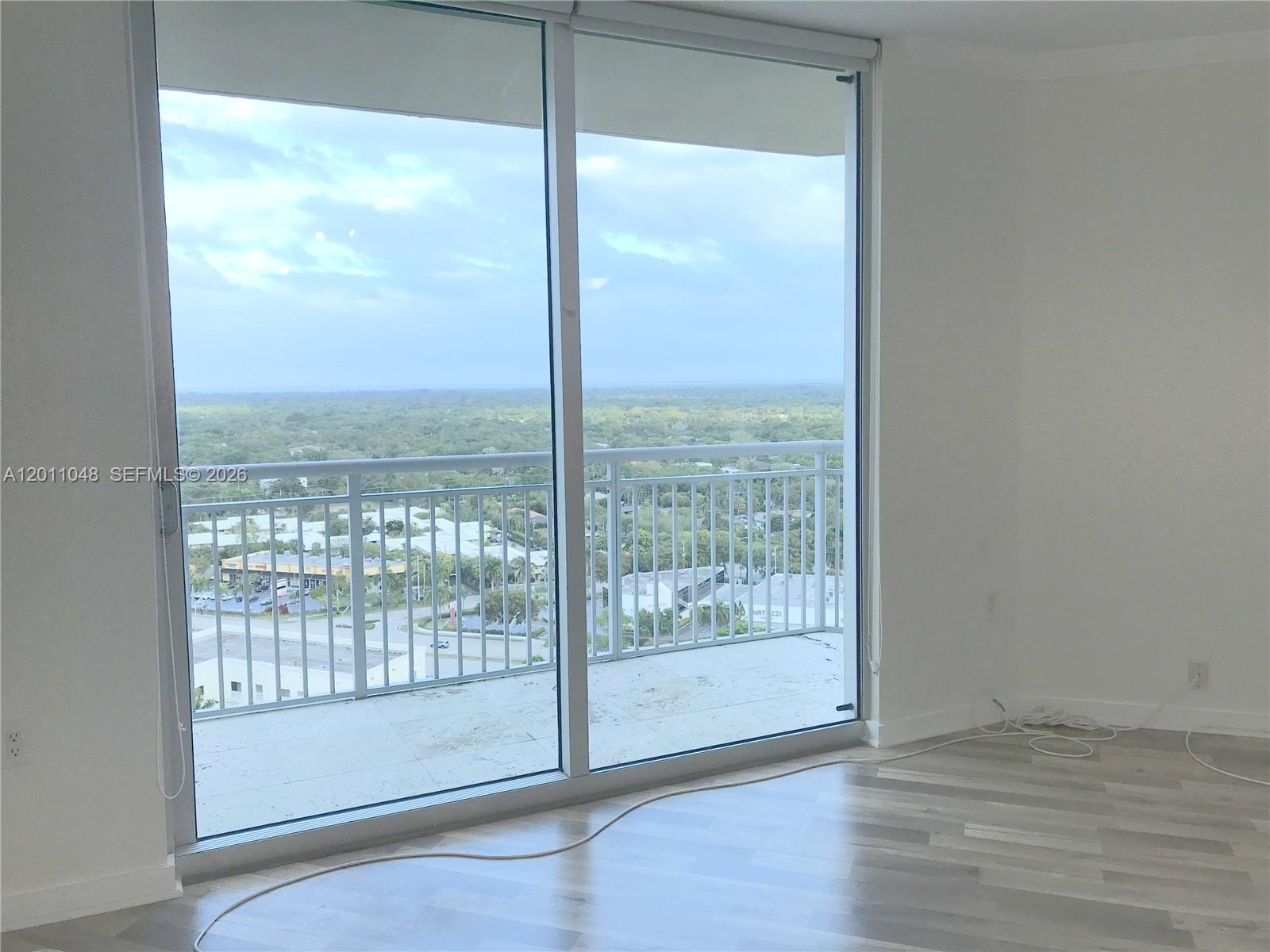 An empty room with light wood flooring features floor-to-ceiling windows leading to a balcony — 9055 SW 73rd Ct # 1903, Miami FL 33156, MIAMI, FL