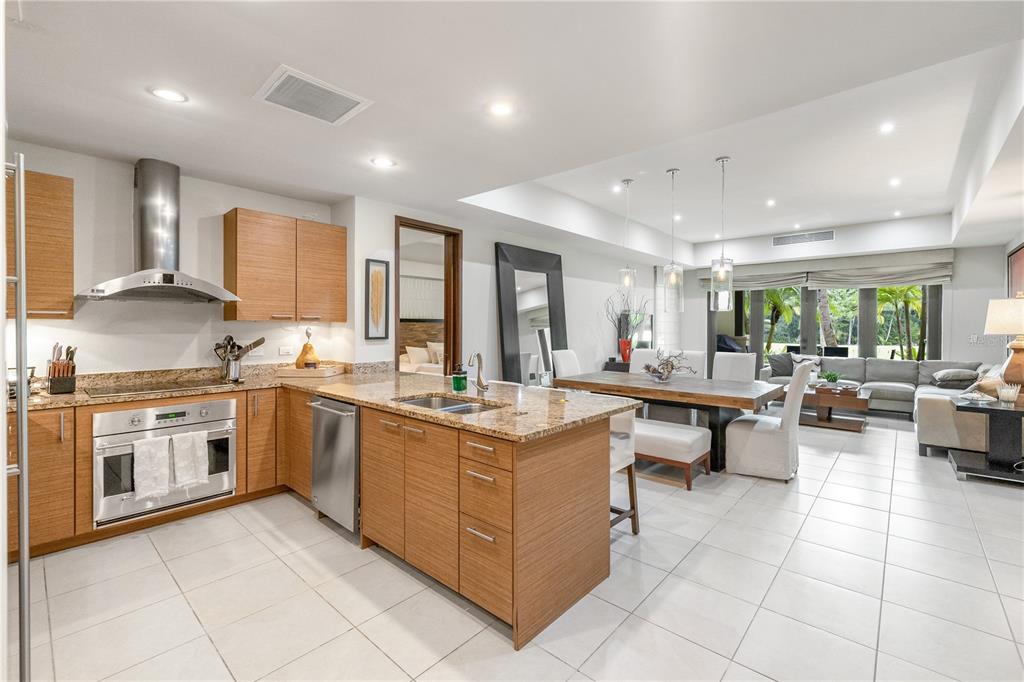 A modern open-concept kitchen and dining area with wood cabinetry, granite countertops, and tile flooring — Bahia Beach Golf Club LAS VERANDAS CONDOMINIUM UNIT 5134, RIO GRANDE, PR