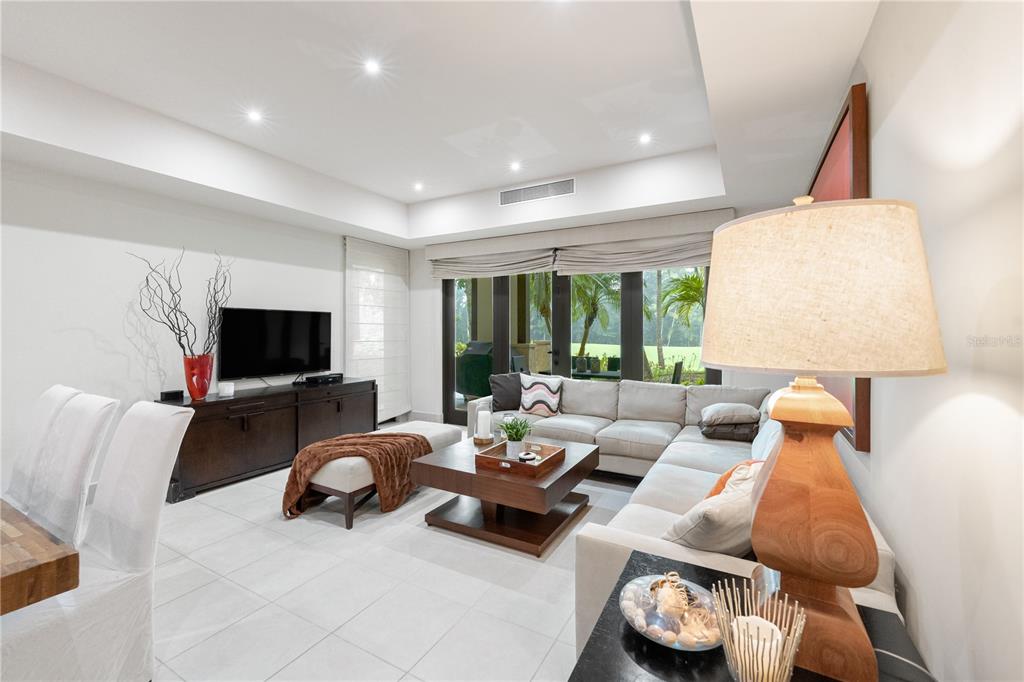 A modern living room features a sectional sofa, coffee table, television, and large glass doors — Bahia Beach Golf Club LAS VERANDAS CONDOMINIUM UNIT 5134, RIO GRANDE, PR