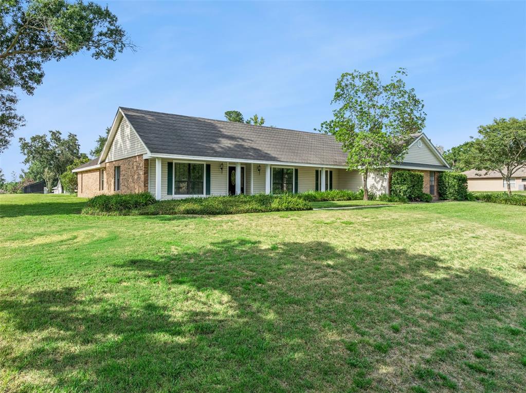 A single-story house with a brick and siding exterior sits on a large grassy lot — 9225 MCDAVID COURT, WINDERMERE, FL