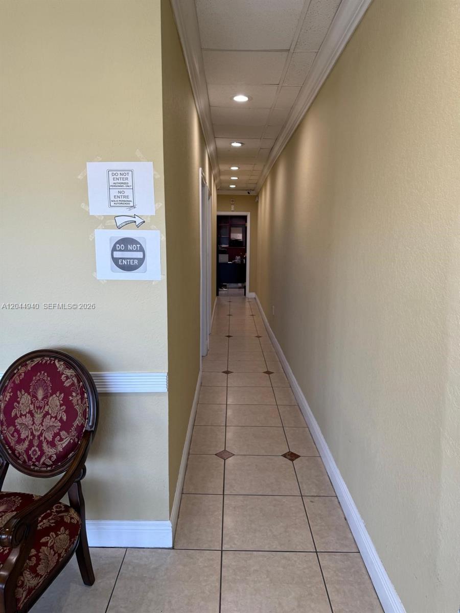 A narrow hallway with beige walls, tile flooring, and a drop ceiling leads to a doorway — 3700 W 12th Ave Suite 3762, Hialeah FL 33012, HIALEAH, FL