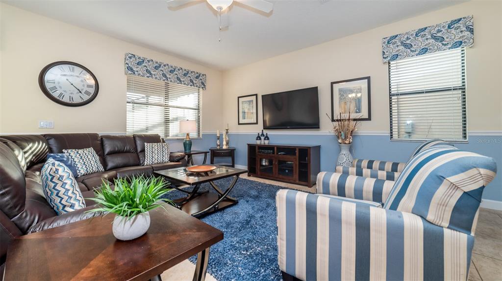 A living room features a dark leather sectional, striped armchairs, and a blue area rug — 1506 MOON VALLEY DRIVE, DAVENPORT, FL