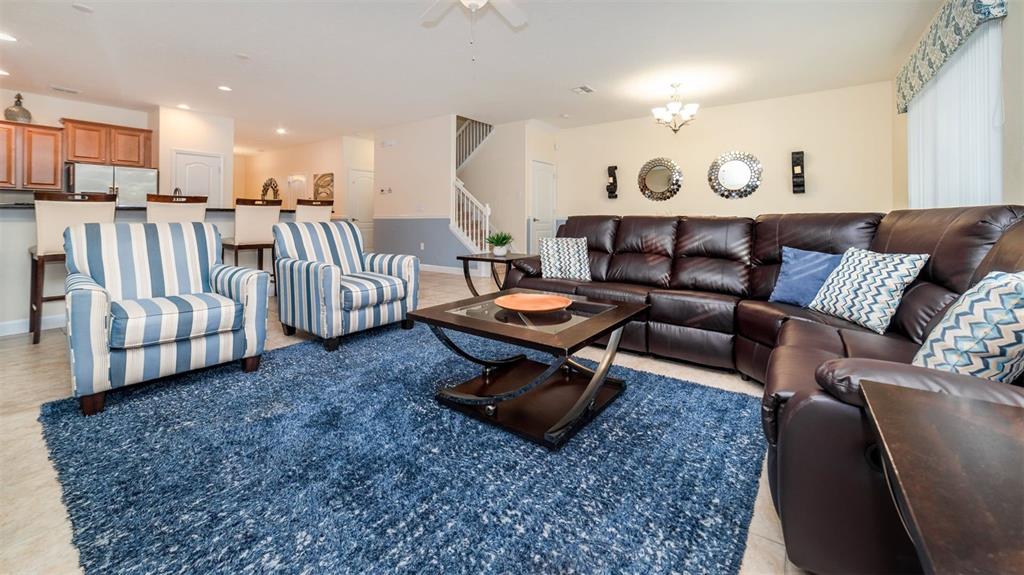 A living room features a dark leather sectional, two striped armchairs, and a blue rug — 1506 MOON VALLEY DRIVE, DAVENPORT, FL