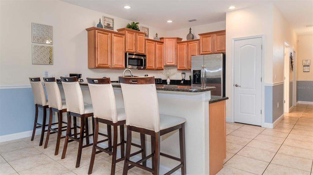 A kitchen features light wood cabinets, stainless steel appliances, a breakfast bar, and tile flooring — 1506 MOON VALLEY DRIVE, DAVENPORT, FL